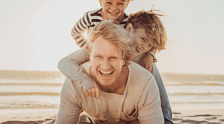 Father and his to sons on the beach smiling